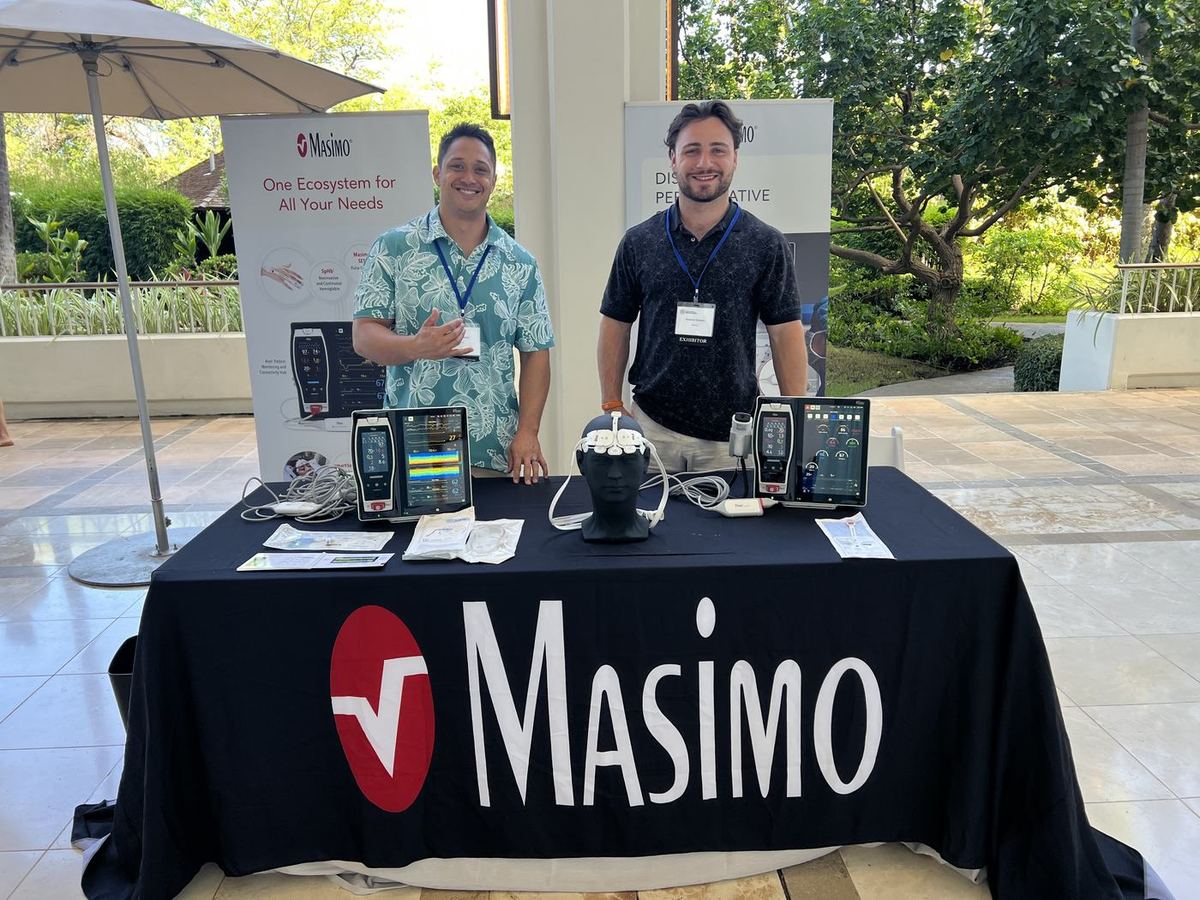 Two representatives behind a draped CSA exhibit table with patient monitors